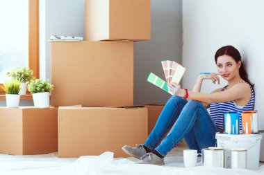 Kadın seçerek boya rengi renk örneği yeni ev ahşap yere oturmak için. Kadın evde