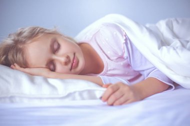 çocuk oyuncak oyuncak ayı ile yatakta uyur küçük kız.