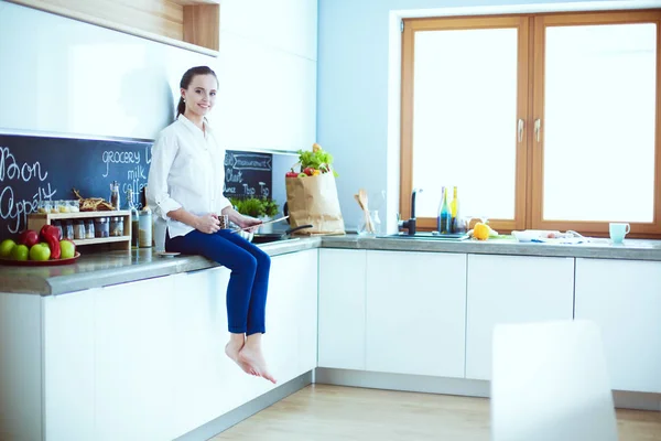 Retrato de mujer joven de pie sobre el fondo de la cocina . —  Fotos de Stock