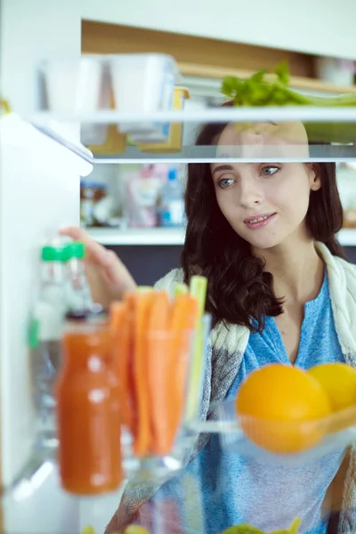 Portrait of female standing near open fridge full of healthy food, vegetables and fruits. Portrait of female — Stock Photo, Image