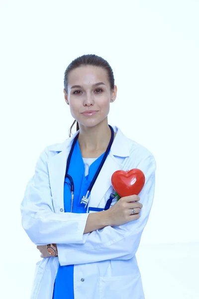 Positive female doctor standing with stethoscope and red heart symbol isolated. Woman doctor — Stock Photo, Image