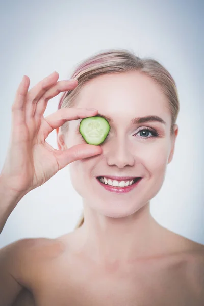 Mooie jongedame met plakjes komkommer op witte achtergrond. — Stockfoto