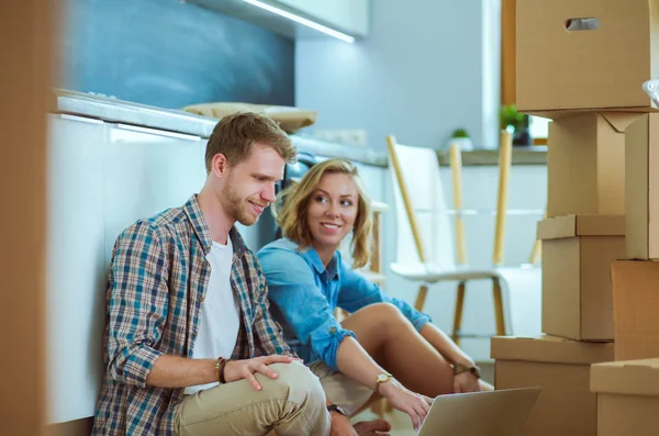 Genç bir çift yeni ev içinde hareket. Oturma ve açma sonra rahatlatıcı. Bir şey üstünde laptop arıyorum. Genç Çift