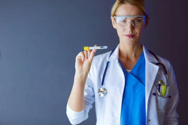 Ženská lékařka nebo výzkumná vědkyně nebo lékařka, která se dívá na zkumavku s čirým roztokem v laboratoři nebo laboratoři. — Stock fotografie