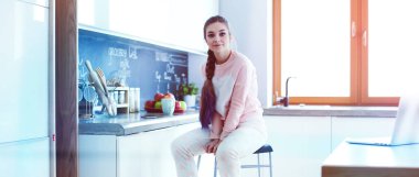 Mutfakta masada oturan genç kadın.