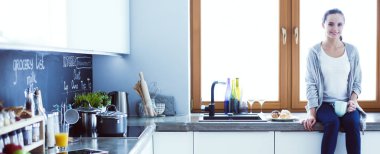 Mutfakta dijital tablet kullanan güzel genç bir kadın..