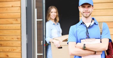 Mavi üniformalı gülümseyen kurye servis konseptine paket kutusu teslim eden teslimatçı. Mavi üniformalı gülümseyen teslimatçı.