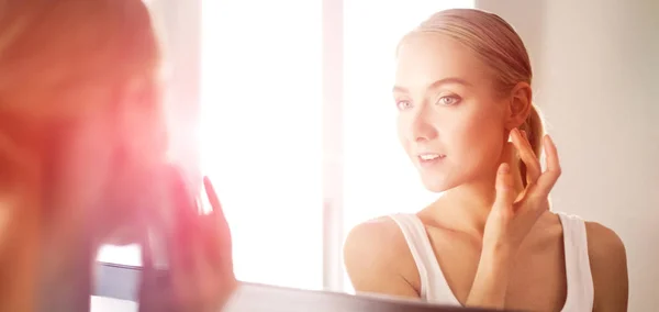 Woman caring of her beautiful skin on the face standing near mirror — Stock Photo, Image