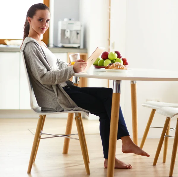 Mutfakta portakal suyu ve tableti olan genç bir kadın..