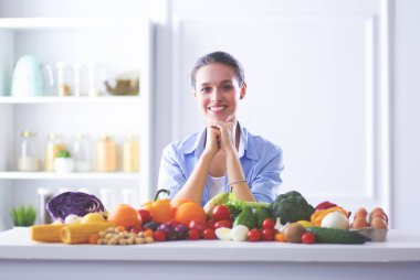 Ahşap iç kısımda meyve ve sebze dolu masada oturan genç ve tatlı bir kadın..