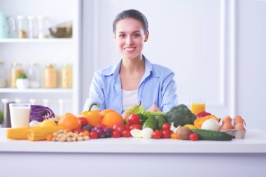 Ahşap iç kısımda meyve ve sebze dolu masada oturan genç ve tatlı bir kadın..