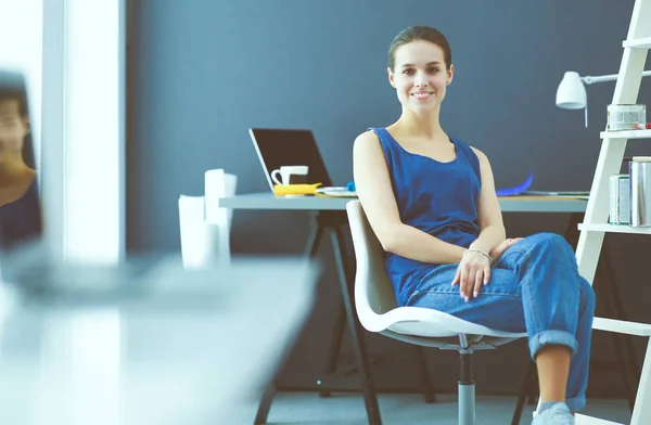 Giovane donna seduta alla scrivania con strumenti, piano e laptop. — Foto Stock