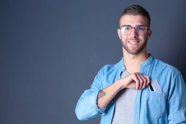 Gri arka planda duran bir kredi kartı tutan genç adam. Genç girişimci..