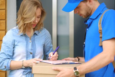 Mavi üniformalı gülümseyen kurye servis konseptine paket kutusu teslim eden teslimatçı. Mavi üniformalı gülümseyen teslimatçı.