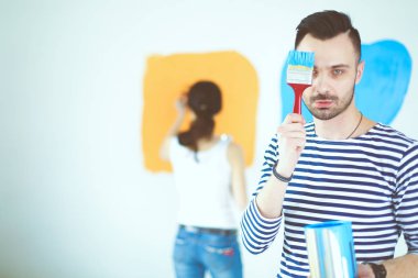 Yeni evin içini boyayan mutlu, genç bir çiftin portresi. Genç çift
