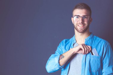 Gri arka planda duran bir kredi kartı tutan genç adam. Genç girişimci..