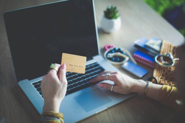 Genç bir kadın kahve molasında ya da kahve molasında dizüstü bilgisayar kullanıyor..