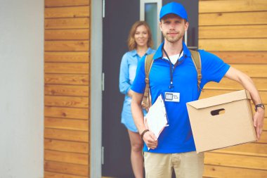 Mavi üniformalı gülümseyen kurye servis konseptine paket kutusu teslim eden teslimatçı. Mavi üniformalı gülümseyen teslimatçı.
