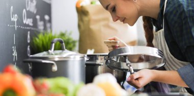 Mutfakta sobanın yanında duran genç bir kadın. .