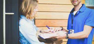 Mavi üniformalı gülümseyen kurye servis konseptine paket kutusu teslim eden teslimatçı. Mavi üniformalı gülümseyen teslimatçı.