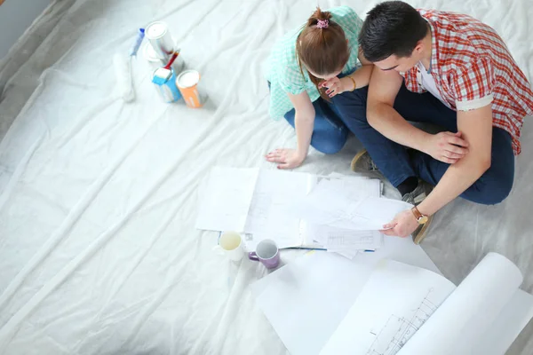 Pareja joven sentada en el suelo y calculando sobre sus ahorros. Pareja joven —  Fotos de Stock