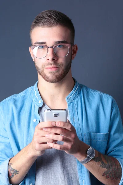 Улыбающийся молодой человек держит телефон во время отправки смс — стоковое фото