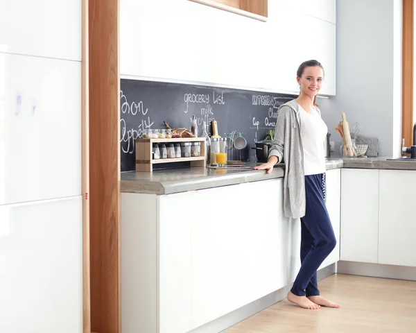 Mujer joven con jugo de naranja y tableta en la cocina. —  Fotos de Stock