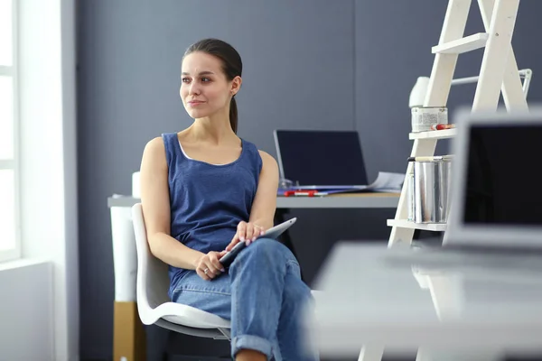 Giovane donna seduta alla scrivania con strumenti, piano e laptop. — Foto Stock