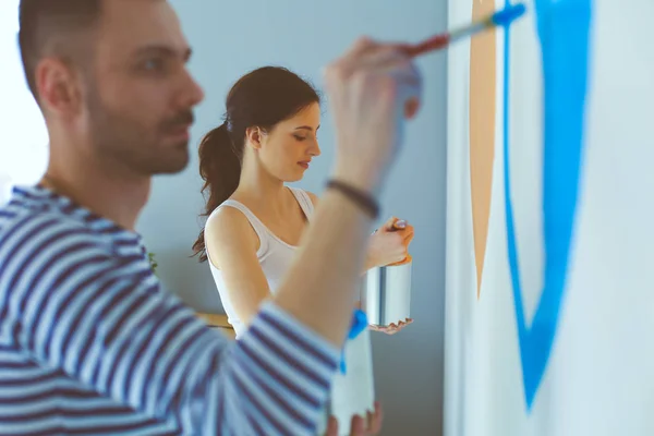 Portrait of happy smiling young couple painting interior wall of new house. young couple — Stock Photo, Image