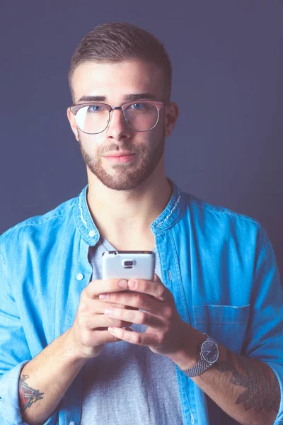 Usmíval se mladý muž držení telefonu při zasílání textových zpráv — Stock fotografie