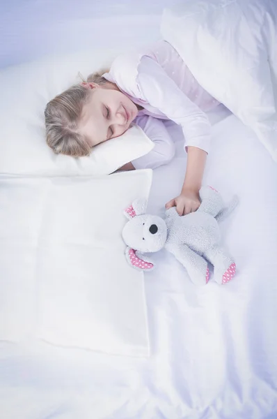 Niño niña duerme en la cama con un osito de peluche de juguete . — Foto de Stock