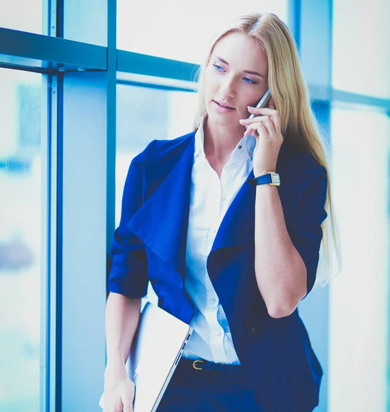 Podnikatelka stojí u okna kanceláře a mluví na mobilu. Obchodnice — Stock fotografie