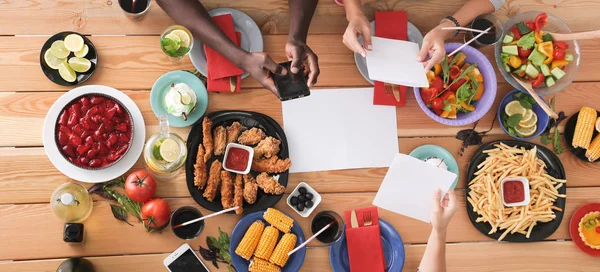 Vue du dessus du groupe de personnes qui dînent ensemble tout en étant assis à une table en bois. De la nourriture sur la table. Les gens mangent fast food. — Photo