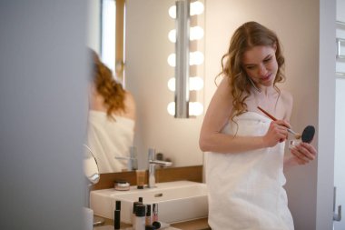 Telefon ile banyo üzerinde duran genç kadın.