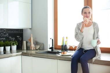 Mutfakta dijital tablet kullanan güzel genç bir kadın..