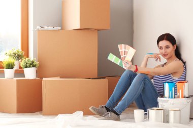 Kadın seçerek boya rengi renk örneği yeni ev ahşap yere oturmak için. Kadın evde