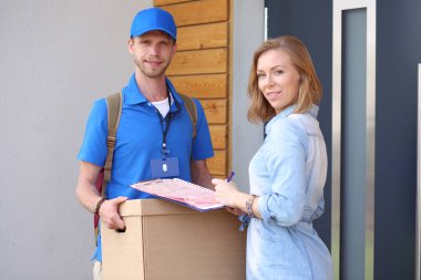 Mavi üniformalı gülümseyen kurye servis konseptine paket kutusu teslim eden teslimatçı. Mavi üniformalı gülümseyen teslimatçı.