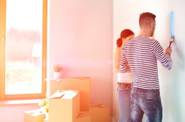 Yeni evin içini boyayan mutlu, genç bir çiftin portresi. Genç çift