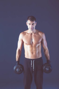 Yakışıklı kaslı adam dumbell ile çalışma dışarı. Kişisel fitness eğitmeni. Kişisel eğitim.
