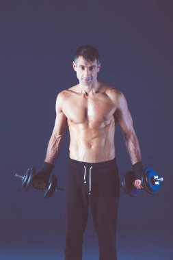 Yakışıklı kaslı adam dumbell ile çalışma dışarı. Kişisel fitness eğitmeni. Kişisel eğitim.