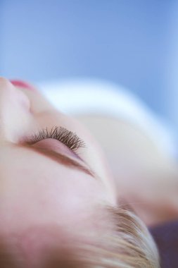 Masaj masasında uzanmış gözleri kapalı rahatlayan genç bir kadın. - Kadın. Spa salonu