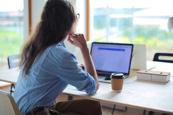 オフィスのテーブルに座っている若い女性は、ノートパソコンのコンピュータ画面を見て。若い女性 — ストック写真