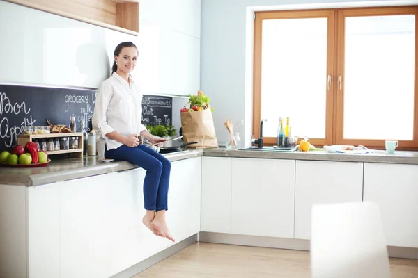 Retrato de mujer joven de pie sobre el fondo de la cocina . — Foto de Stock