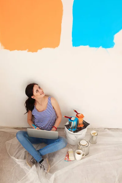 Портрет молодой женщины при покраске новой квартиры, сидя с ноутбуком. Молодая женщина с ноутбуком — стоковое фото
