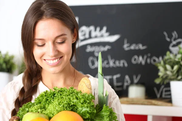 Lächelnde junge Frau mit Gemüse in der Küche. Lächelnde junge Frau — Stockfoto