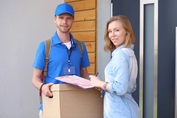 Leende leverans man i blå uniform leverera paket låda till mottagaren - kurir service koncept. Leende leverans man i blå uniform — Stockfoto