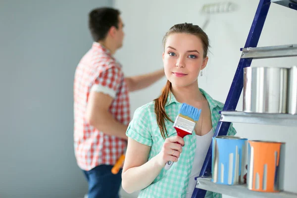 Ritratto felice sorridente giovane coppia pittura parete interna della nuova casa. Coppia giovane — Foto Stock