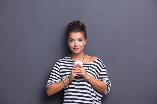 Jeune femme debout avec tasse, isolée sur fond gris. Jeune femme — Photo