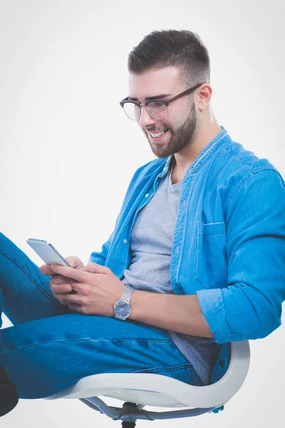 Mladý muž sedí na židli a pomocí mobilního telefonu. Startupper. Mladý podnikatel. — Stock fotografie