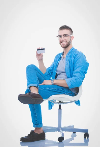 Joven sentado en la silla y con tarjeta de crédito. Startupper. Joven empresario . — Foto de Stock